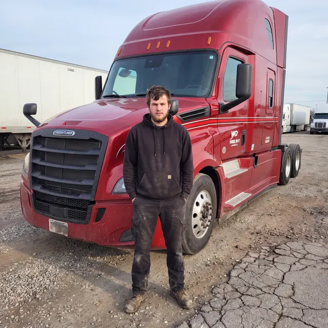Truck driver standing with a Wheel Do It Logistics truck